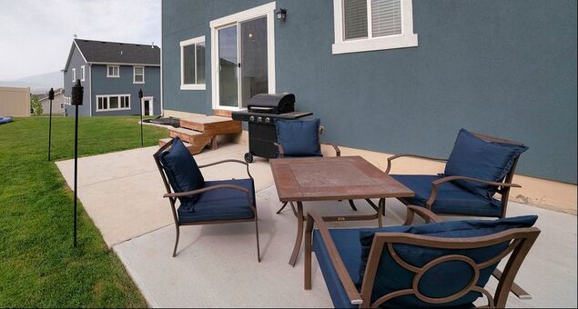 A concrete patio that was lifted and re-leveled after sinking into the ground, with patio furniture and a grill.